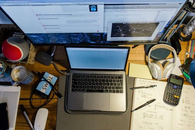 a messy desk with a laptop and various items