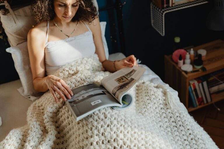 woman looking at a magazine on bed