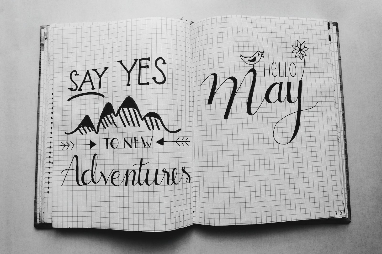 Black and white image of an open journal featuring motivational quotes and artistic doodles.