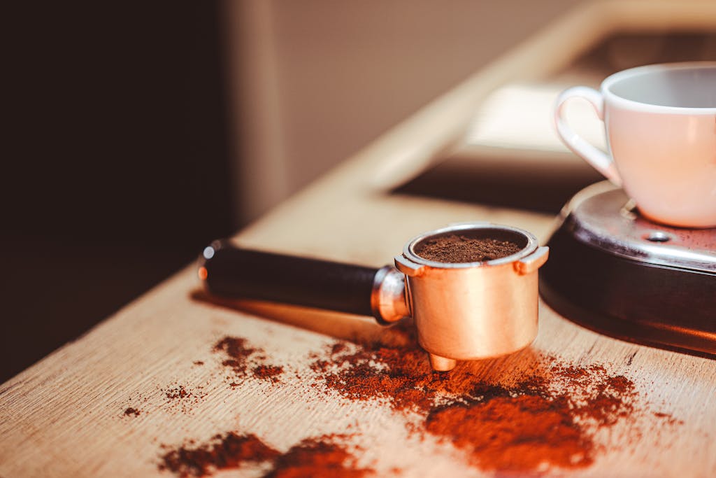 A close-up shot of a coffee portafilter next to a cup, highlighting espresso preparation.