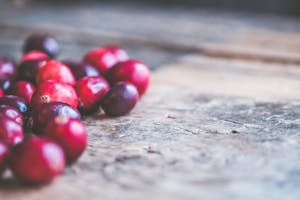 A rustic close-up view showing vibrant red cranberries scattered on a wooden surface.