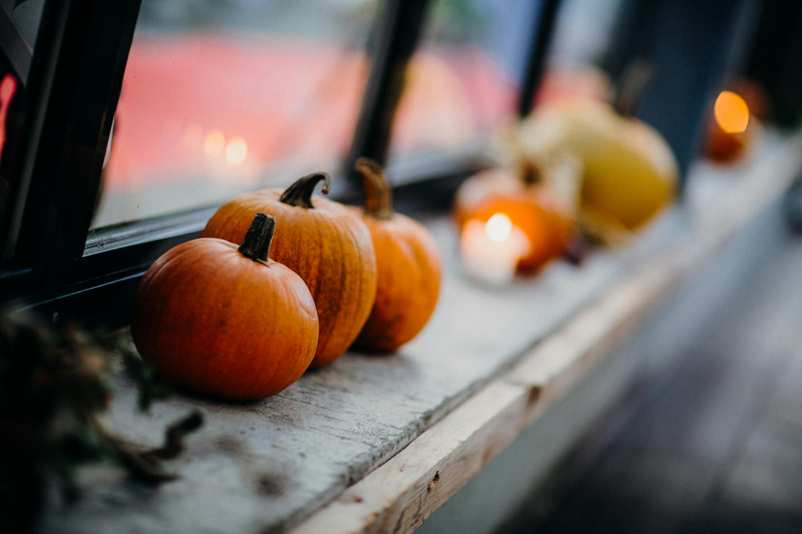 Close-up of pumpkins on a window sill during fall, creating a warm, seasonal atmosphere.
