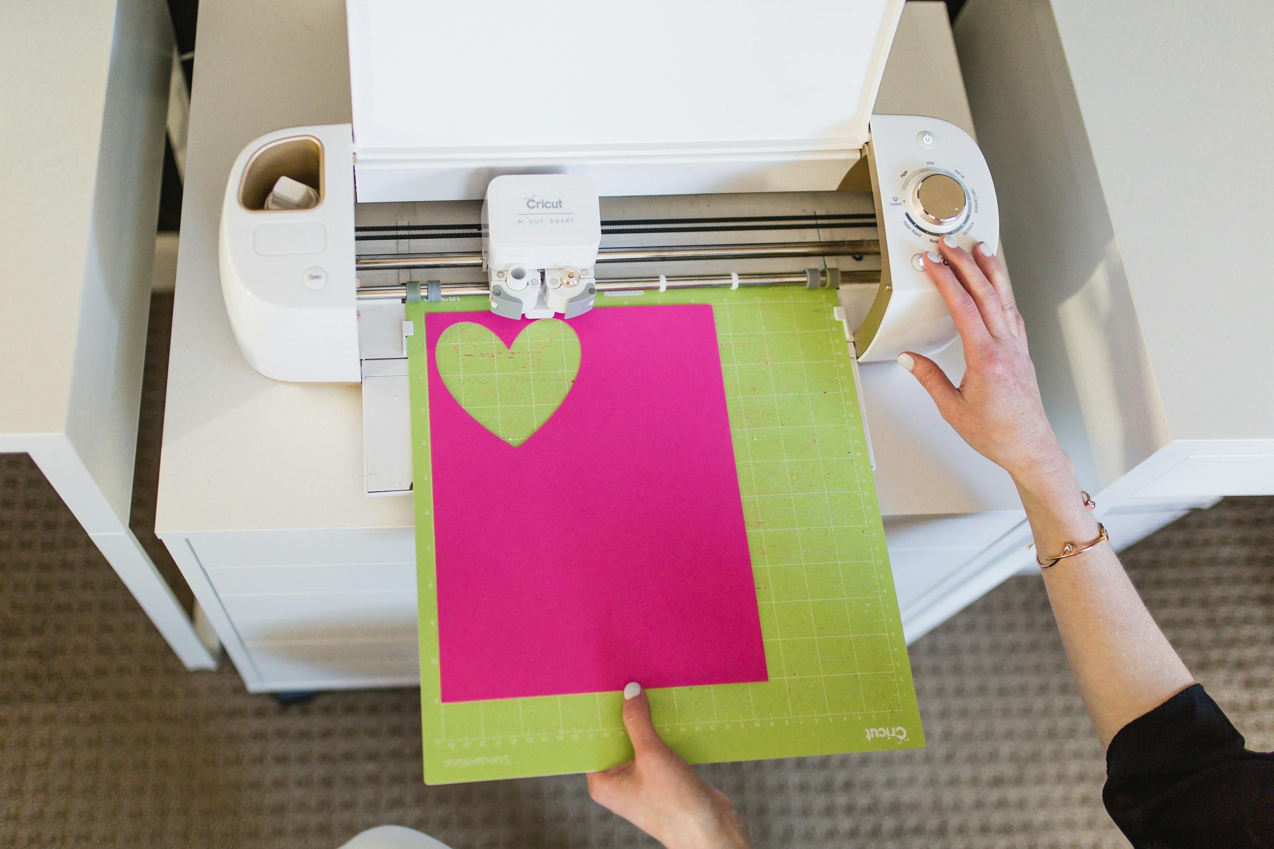Overhead view of a cutting machine creating a heart shape on pink paper in California City.
