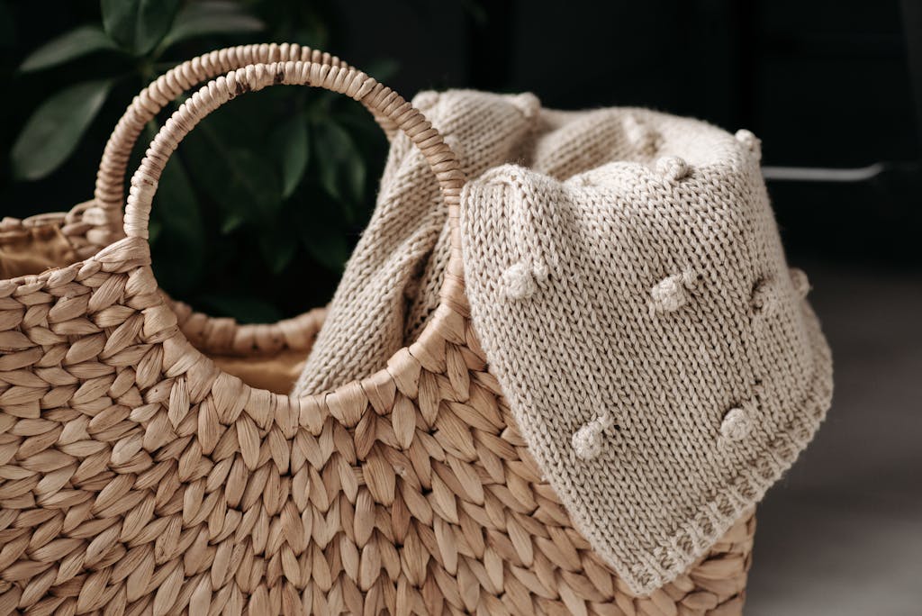 A close-up of a woven basket with a beige knitted blanket draped over it, highlighting texture.