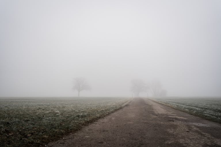 A misty rural landscape with fog covering a road in Bad Feilnbach, Bavaria, Germany.