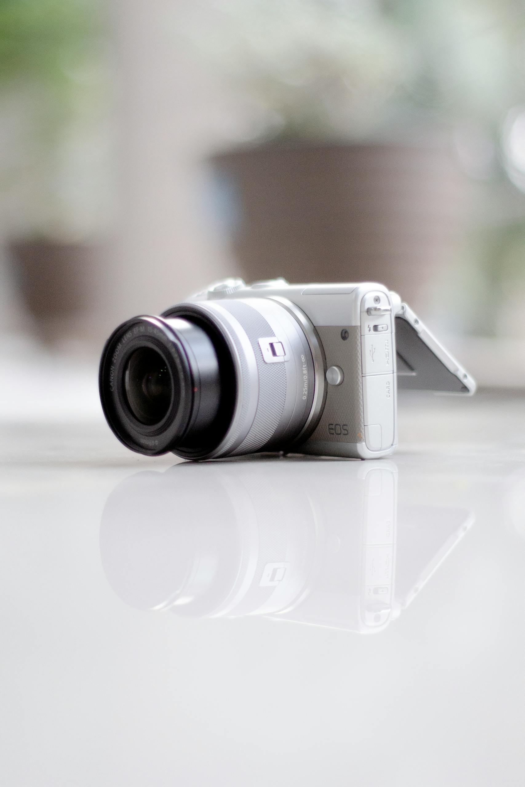 Close-up of a DSLR camera on a reflective surface, emphasizing sleek design and modern technology.