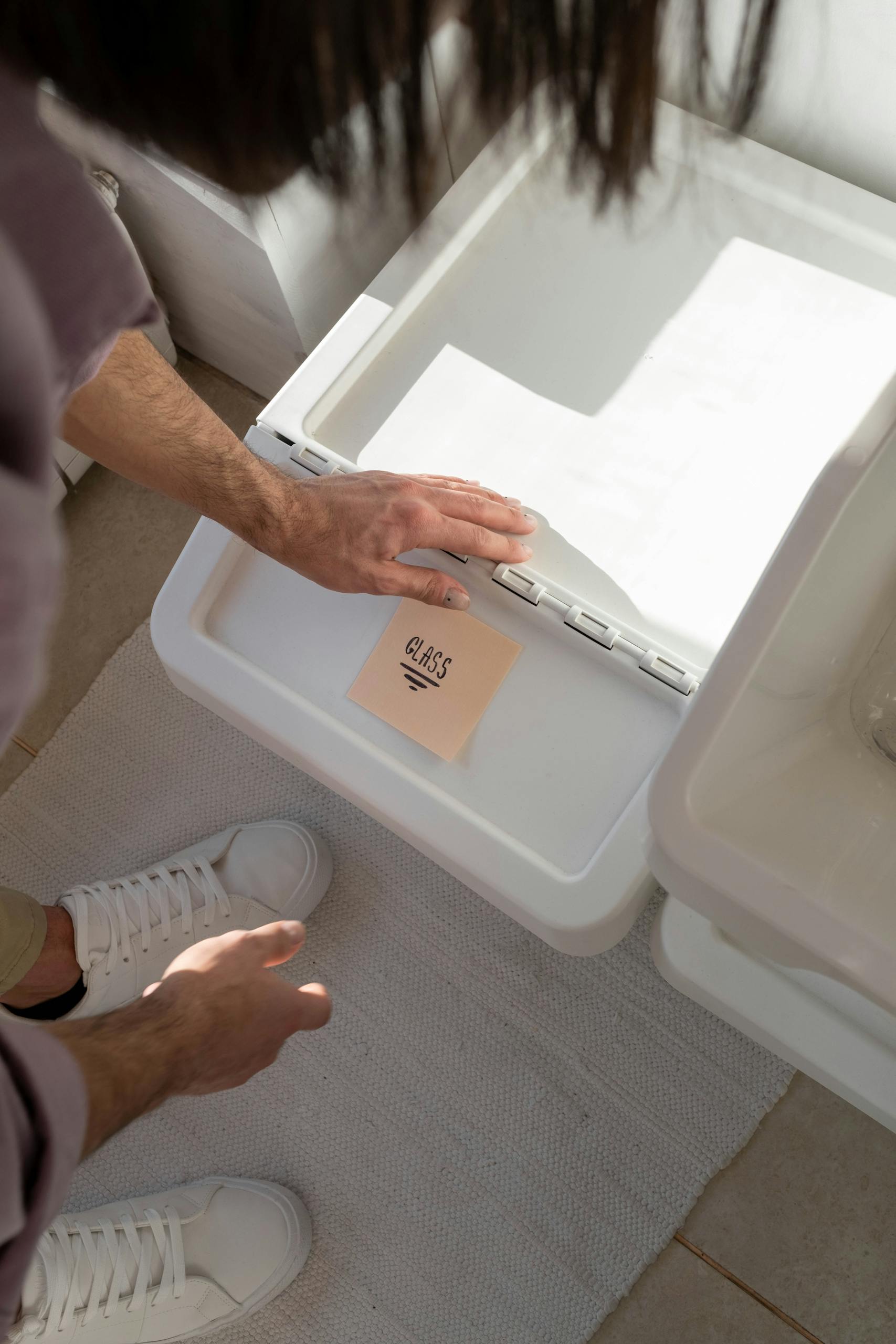 An adult man sorting glass waste in the kitchen for recycling, promoting eco-friendly practices.
